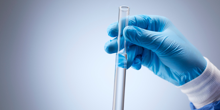 Une personne tient dans sa main un tube à essai rempli d'eau.